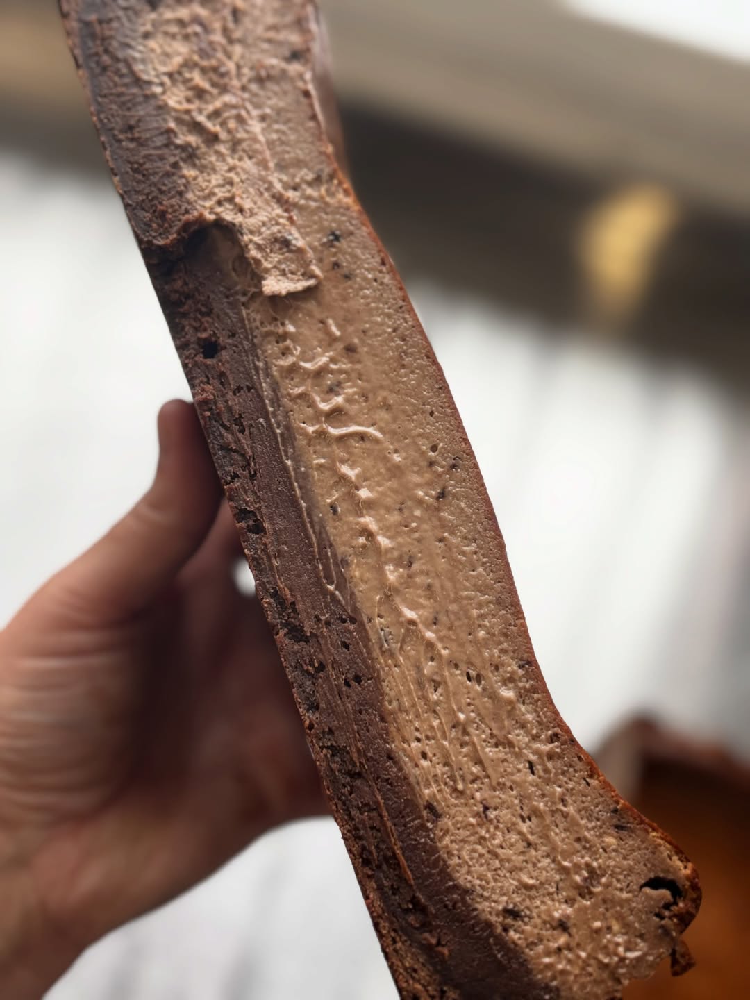 A hand holding a thick chocolate slice